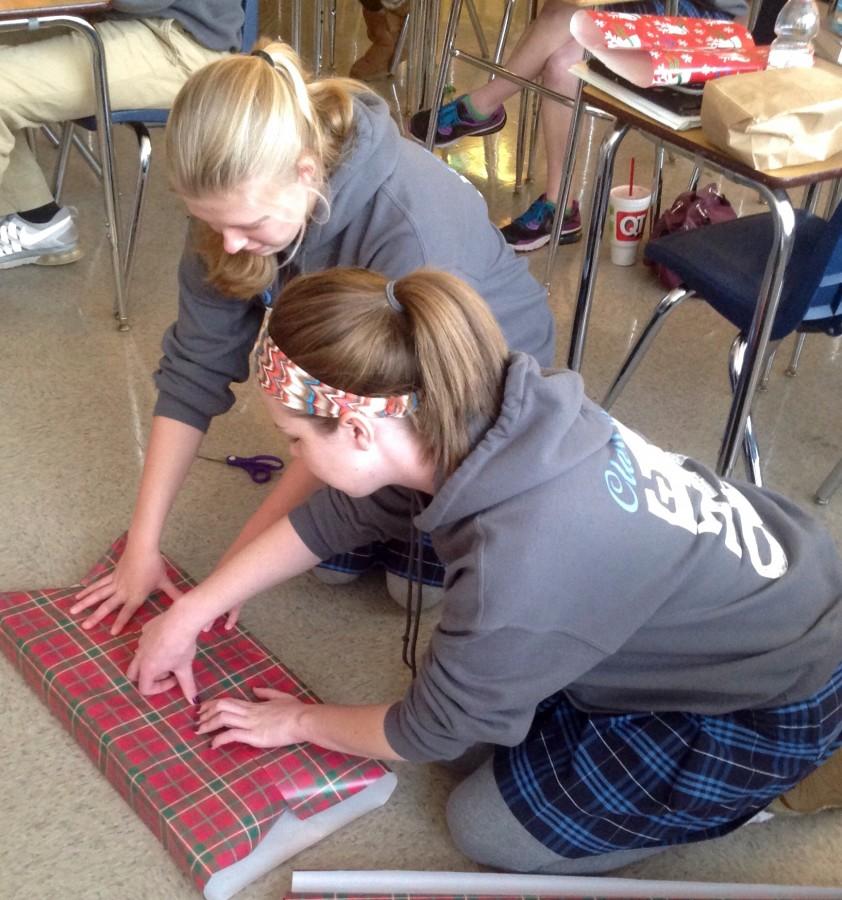 Kristina Brockgreitens and Sarah Brouder wrap presents for the adopted families in Mrs. Johnson's L.E.A.D. class.