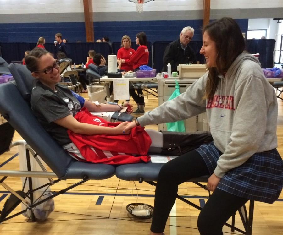 Senior Alison Brendle holding Ms. Zilka's hand while she donates blood. 