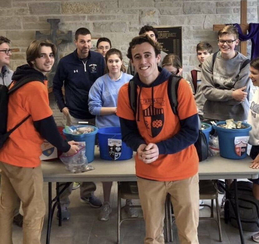 Senior Evan Willie (left) and junior Will Nicholson (right) put silver coins in opposing house buckets.