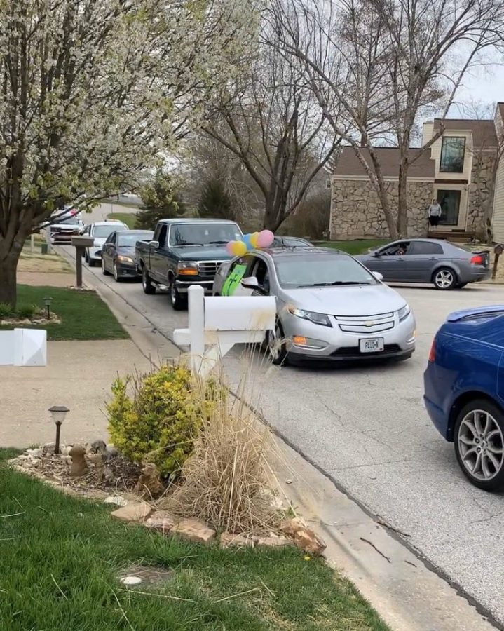 A train of cars filled with friends and family head down the street for a drive-by birthday surprise.
