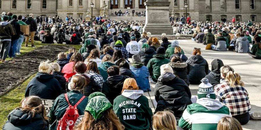 Michigan State students sit outside of the capital in protest.