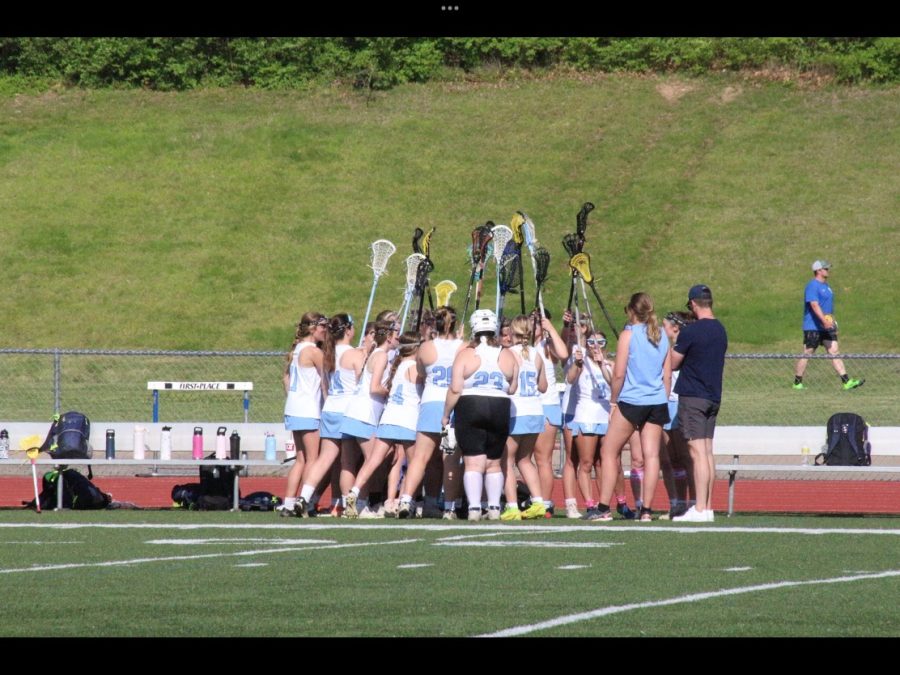 Girls lacrosse celebrates together after a big win at home. 